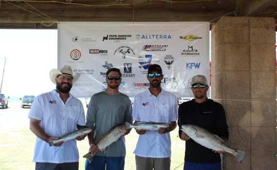 Four team members from Landesign Services, Inc. pose with their catches for charitable fishing tournament